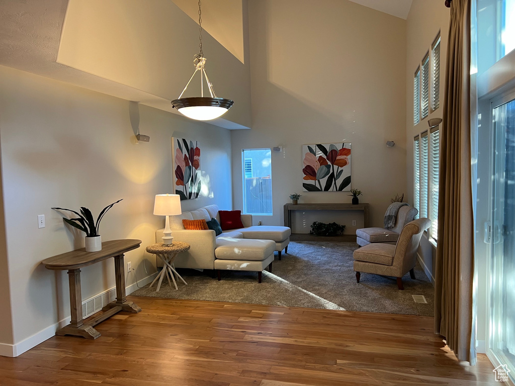 Living area featuring high vaulted ceiling, wood finished floors, plenty of natural light, and baseboards