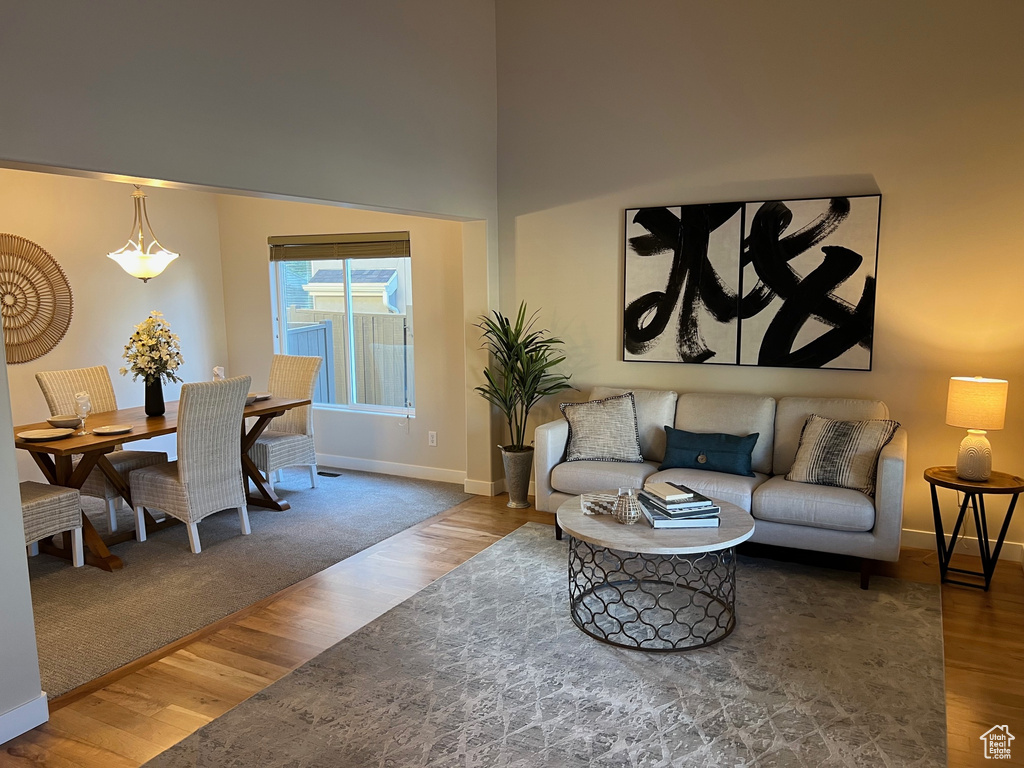 Living area with baseboards, wood finished floors, and a towering ceiling