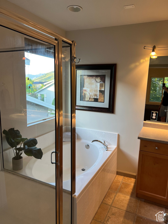 Full bath with vanity, a garden tub, a stall shower, and stone tile floors