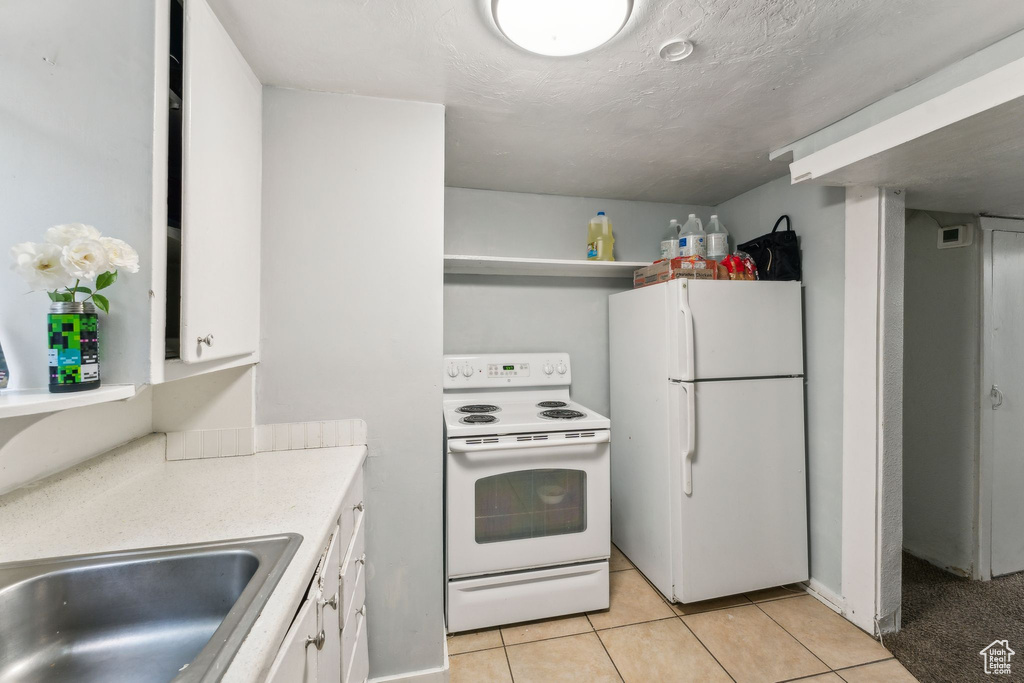 Kitchen featuring white appliances, white cabinetry, light tile patterned flooring, and light countertops