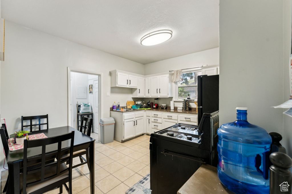 Kitchen with black appliances, white cabinets, light tile patterned floors, and dark countertops