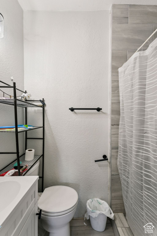 Full bath with a textured wall, vanity, toilet, and a shower with curtain