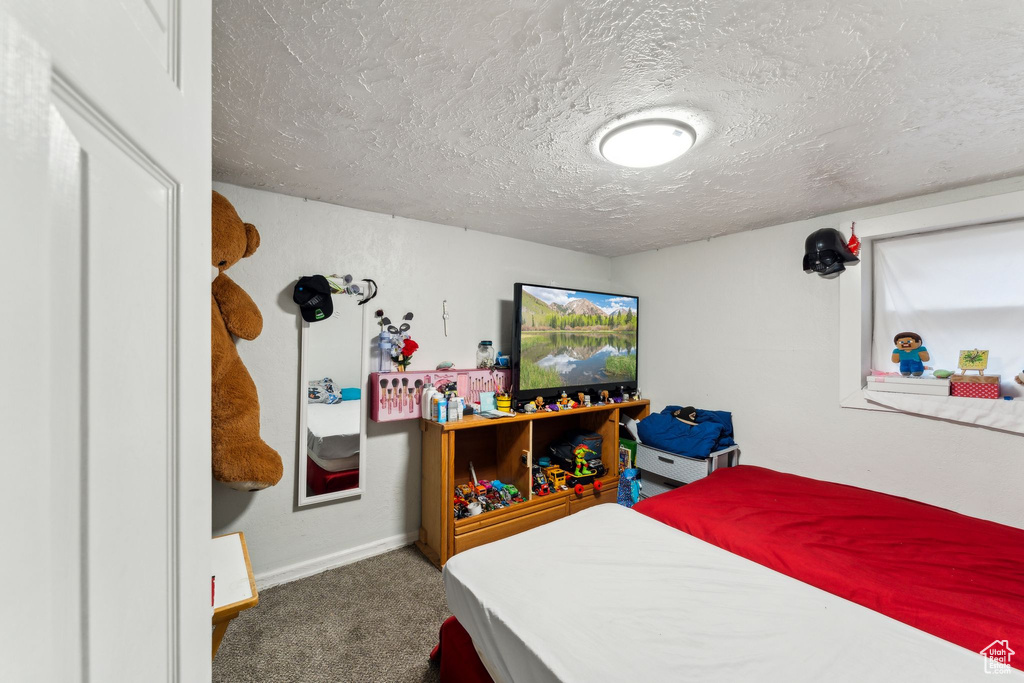 Bedroom with a textured ceiling, carpet, and baseboards