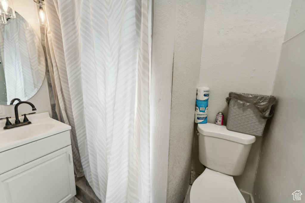 Bathroom with vanity, toilet, and curtained shower