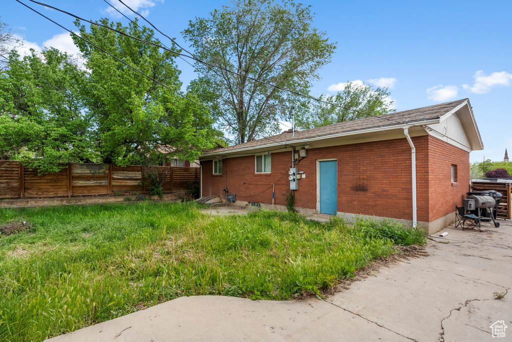 Back of property featuring fence, brick siding, and a patio