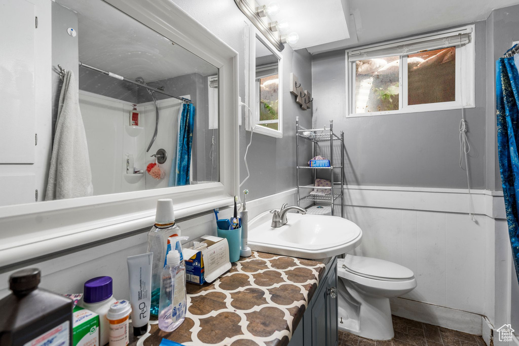 Bathroom with a shower with shower curtain, toilet, wainscoting, and vanity