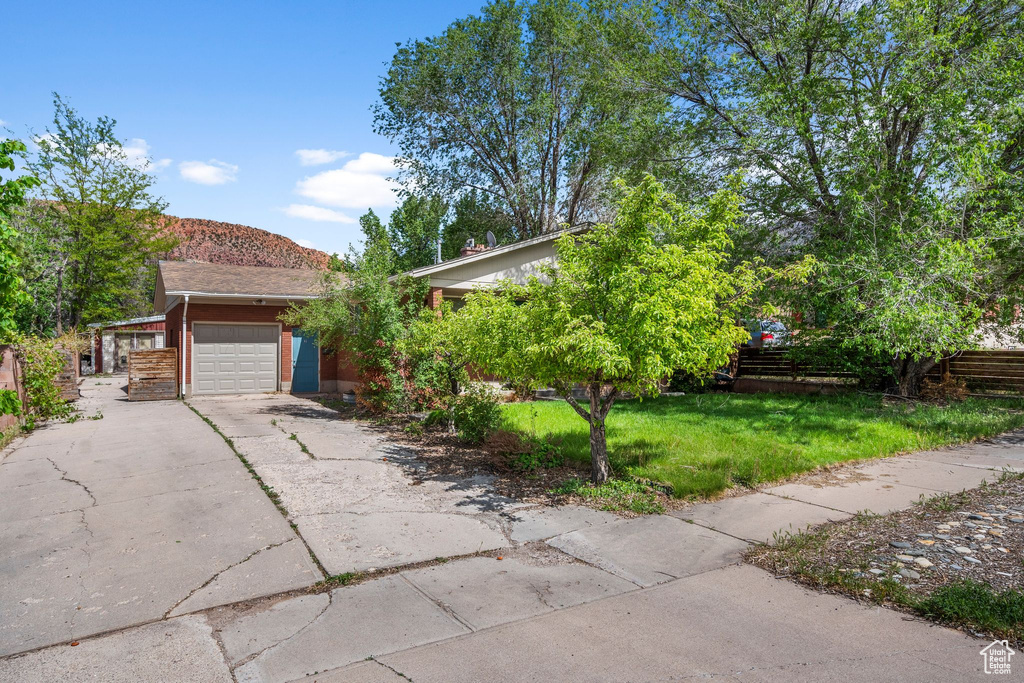 Obstructed view of property featuring an attached garage, driveway, and brick siding