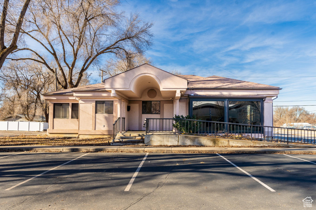 View of front facade with uncovered parking, stucco siding, and covered porch