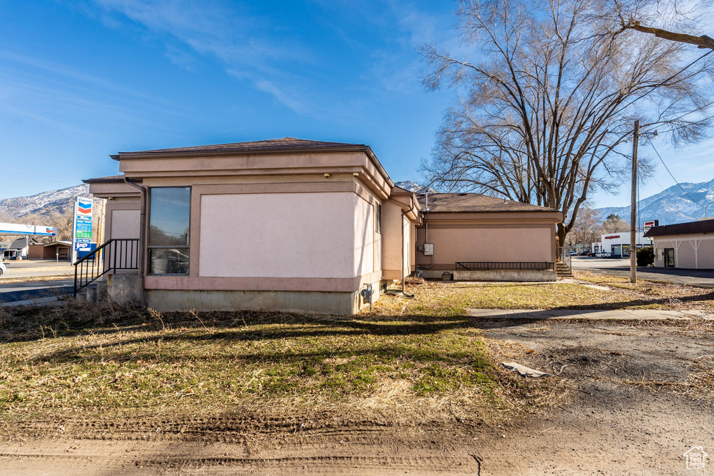 View of property exterior with a mountain view, stucco siding, and entry steps