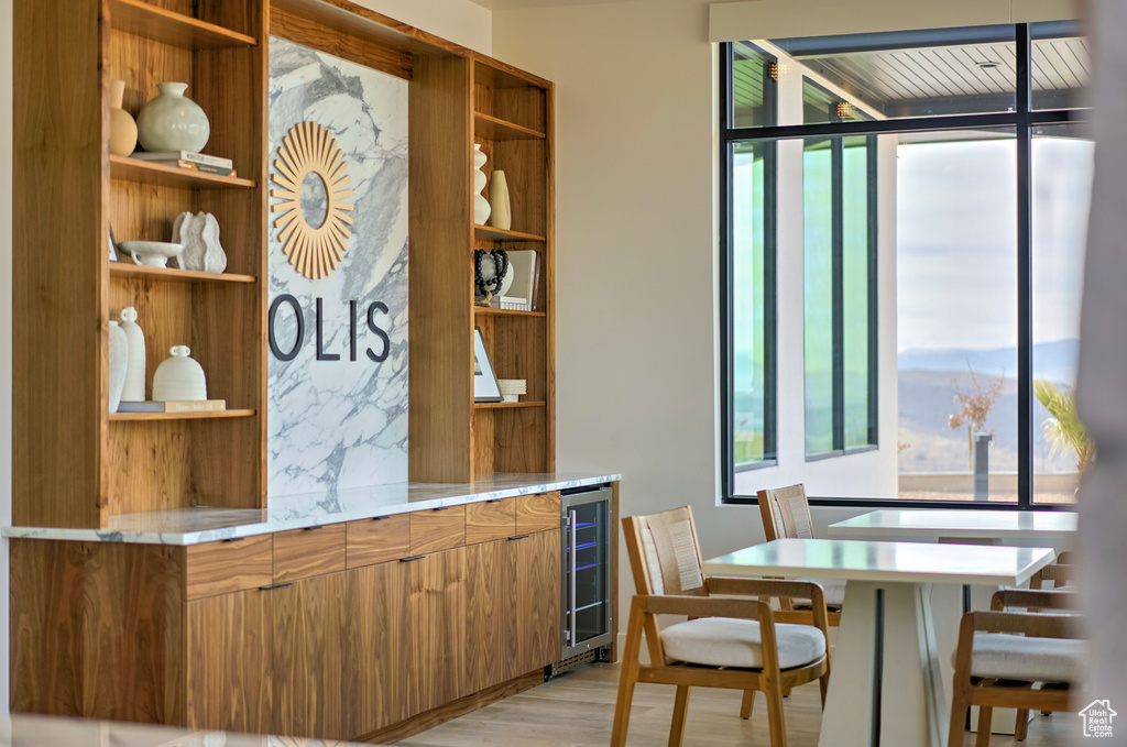 Bar featuring wine cooler, plenty of natural light, light wood finished floors, and backsplash