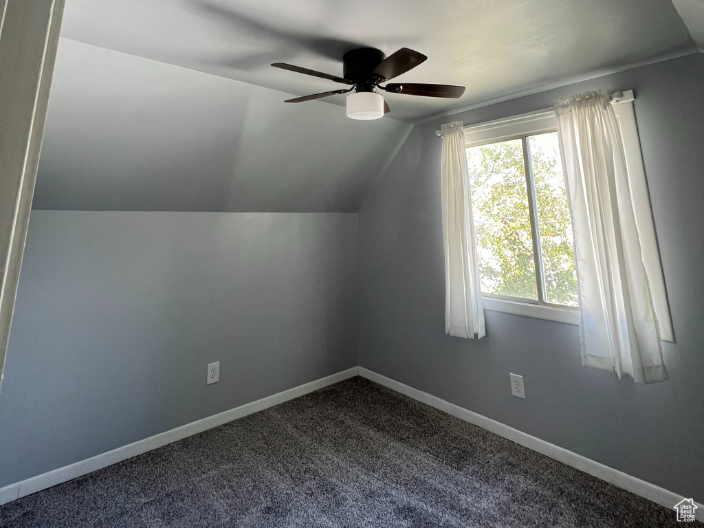 Bonus room with a ceiling fan, vaulted ceiling, dark carpet, and baseboards