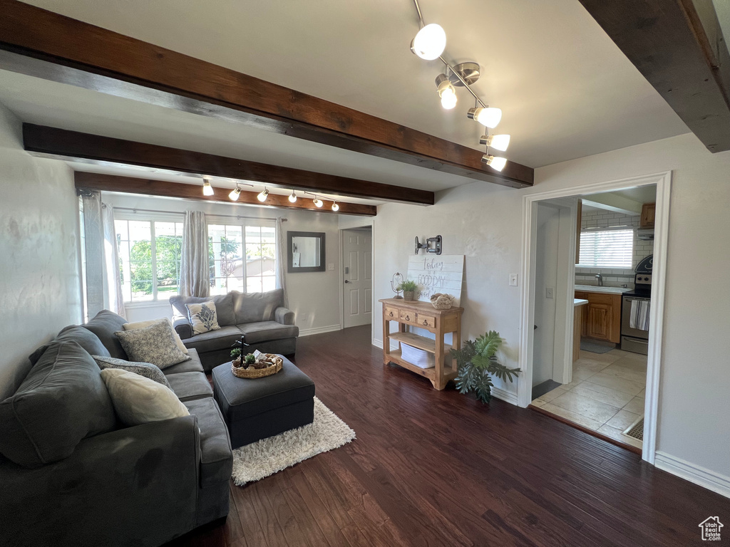 Living area with wood finished floors, beamed ceiling, baseboards, and rail lighting