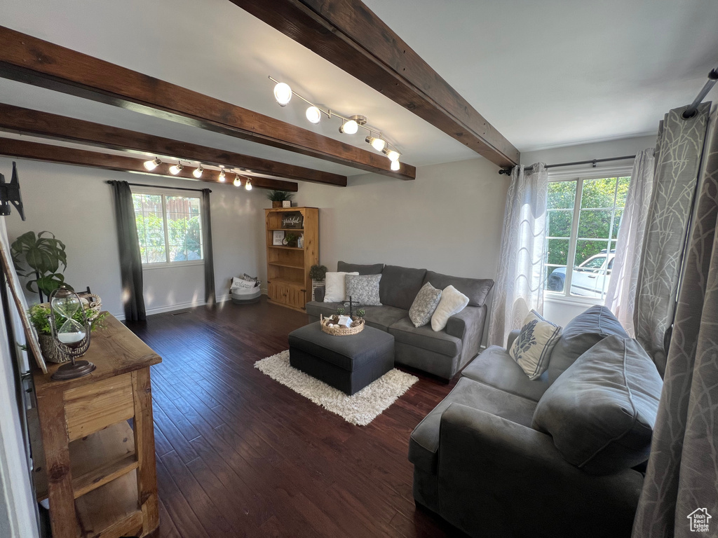 Living area with plenty of natural light, beamed ceiling, dark wood-type flooring, and baseboards