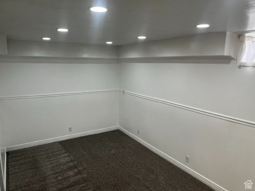 Empty room featuring recessed lighting, dark colored carpet, and baseboards