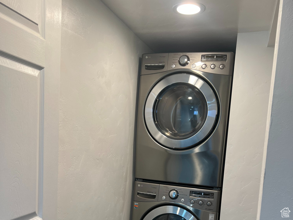 Washroom with stacked washer and clothes dryer, dark wood-type flooring, and baseboards