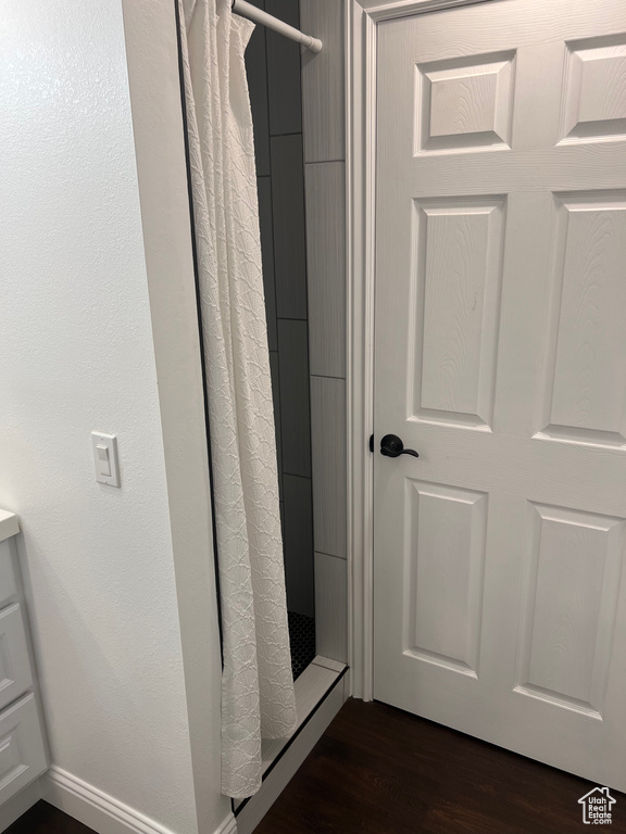 Bathroom with a shower with shower curtain and wood finished floors