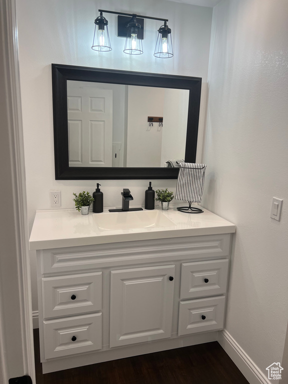 Bathroom with vanity, wood finished floors, and baseboards