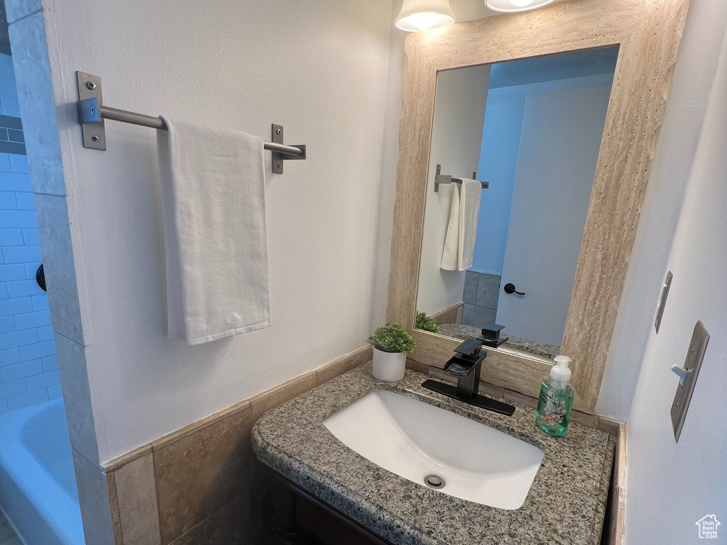 Bathroom featuring vanity, wainscoting, and tile walls