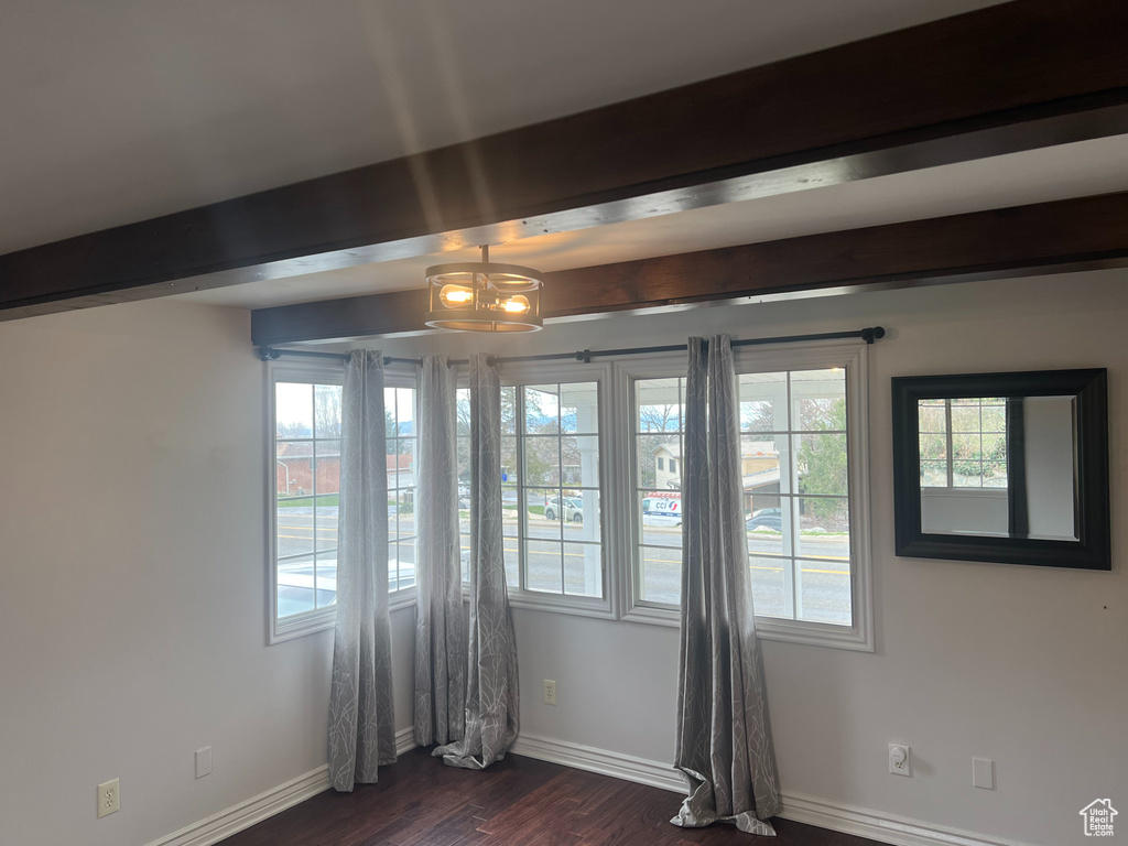 Unfurnished room featuring beamed ceiling, dark wood-style flooring, and baseboards