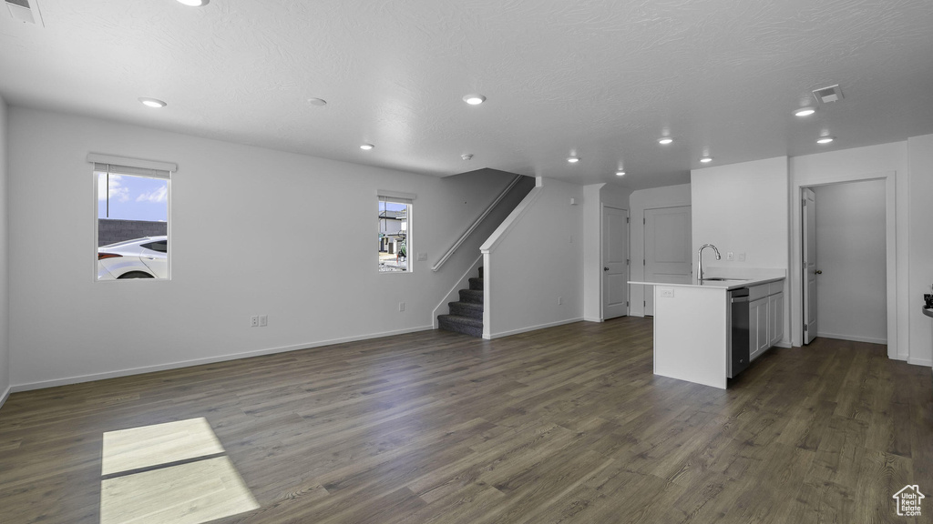 Unfurnished living room featuring recessed lighting, healthy amount of natural light, dark wood-style flooring, stairway, and baseboards
