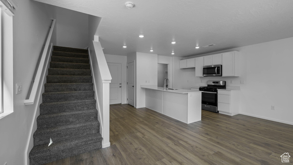 Kitchen with appliances with stainless steel finishes, recessed lighting, light countertops, white cabinetry, and dark wood-type flooring