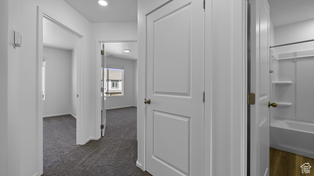 Hall with dark carpet, recessed lighting, and baseboards