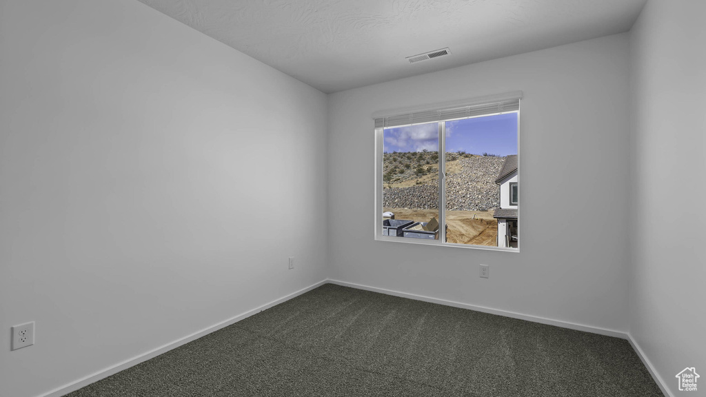 Empty room with dark carpet and baseboards