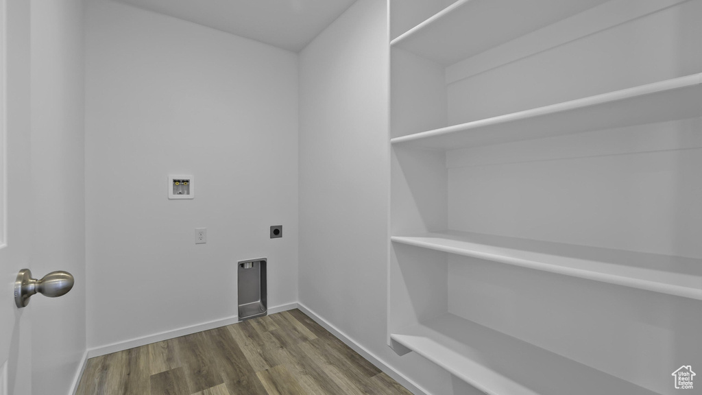 Laundry area featuring electric dryer hookup, hookup for a washing machine, wood finished floors, and baseboards