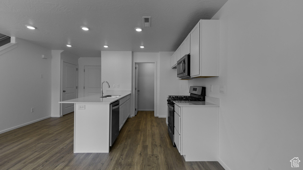 Kitchen with appliances with stainless steel finishes, a peninsula, baseboards, a sink, and recessed lighting