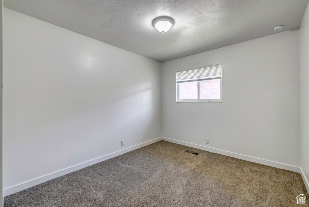 Unfurnished room featuring carpet flooring, baseboards, and a smoke detector