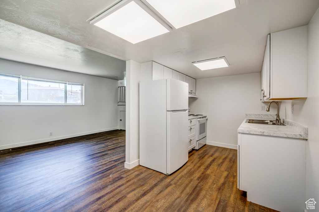 Kitchen featuring white appliances, a sink, dark wood-style floors, and light countertops