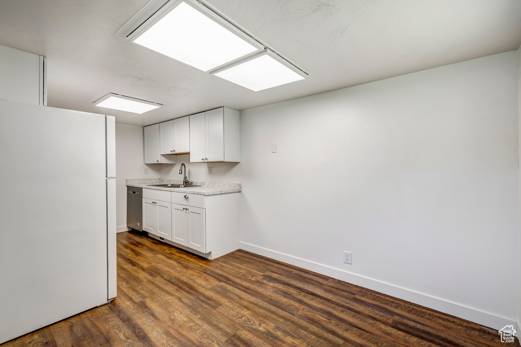 Kitchen with freestanding refrigerator, a sink, light countertops, baseboards, and dark wood finished floors