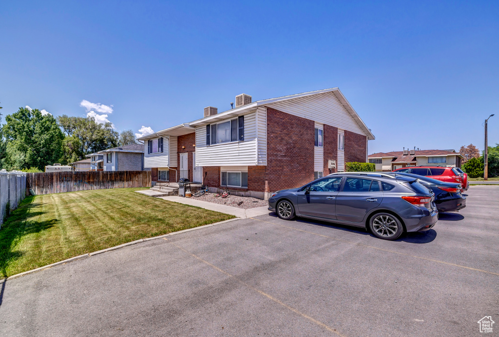 Raised ranch with brick siding, uncovered parking, and a chimney