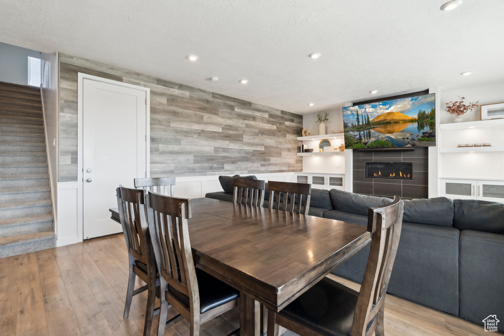 Dining space with stairs, recessed lighting, light wood-type flooring, a fireplace, and wood walls