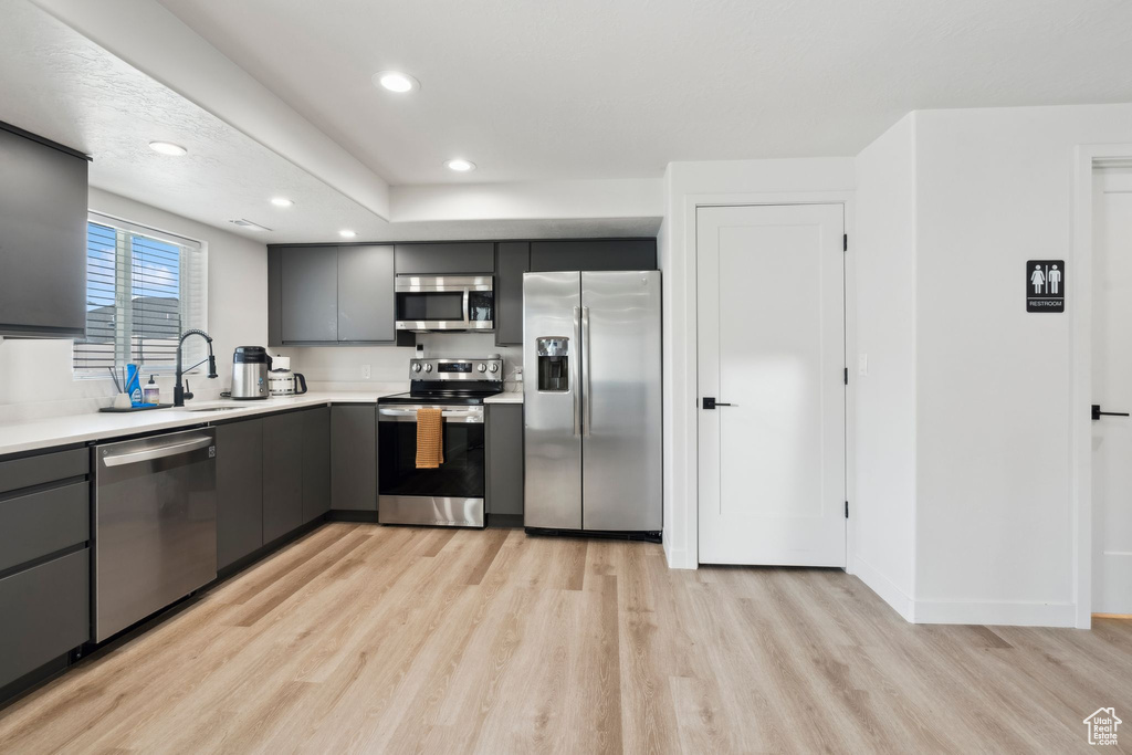 Kitchen with stainless steel appliances, light wood-style floors, gray cabinetry, light countertops, and recessed lighting