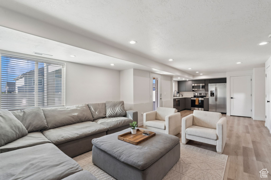 Living area with light wood finished floors, plenty of natural light, recessed lighting, and a textured ceiling