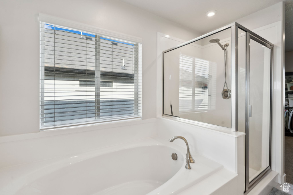 Bathroom featuring a bath, a shower stall, and a walk in closet