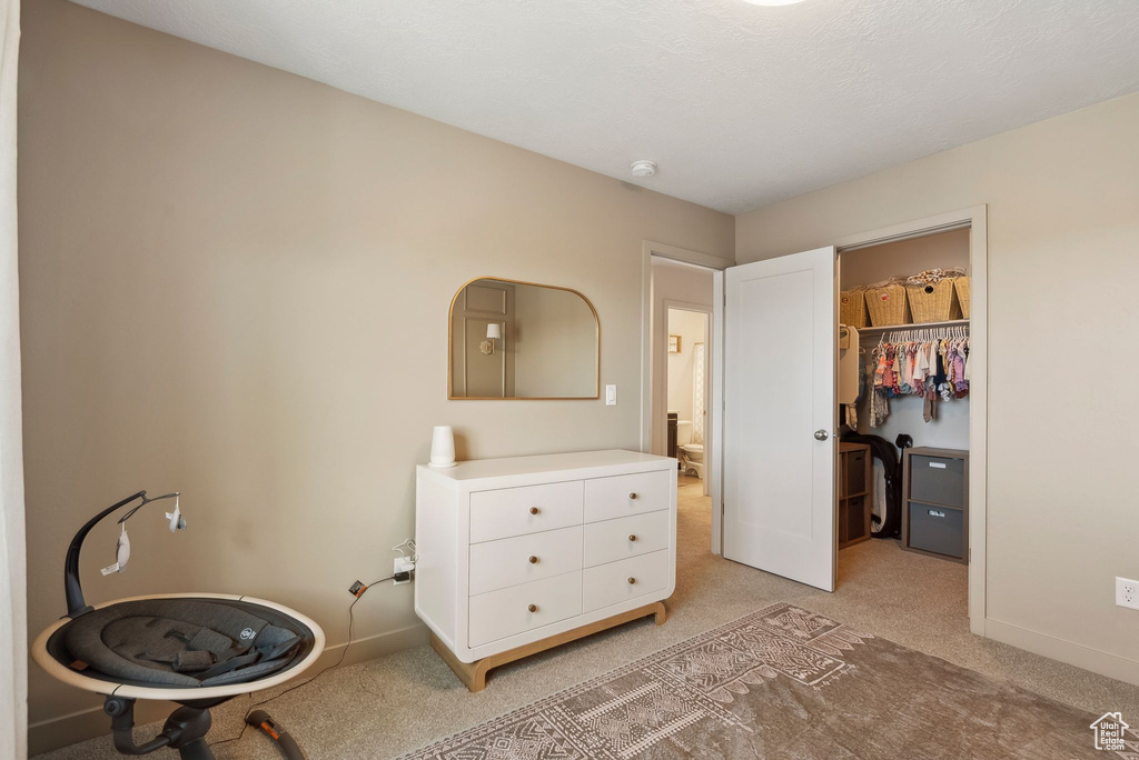 Bedroom with light colored carpet, a walk in closet, baseboards, and a closet