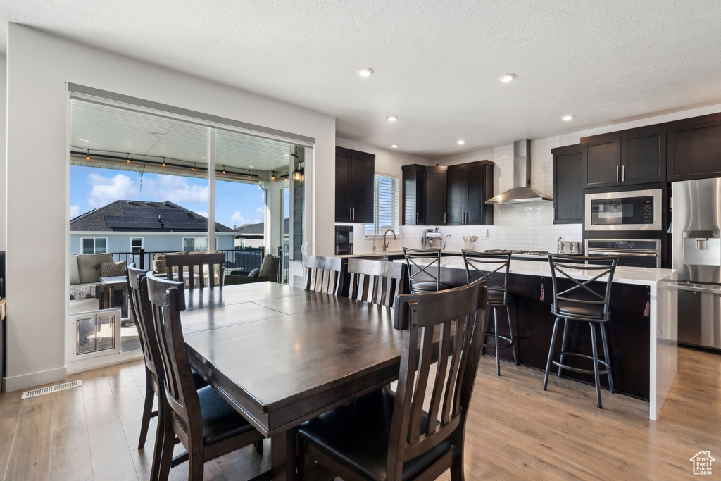 Dining room with light wood finished floors and recessed lighting