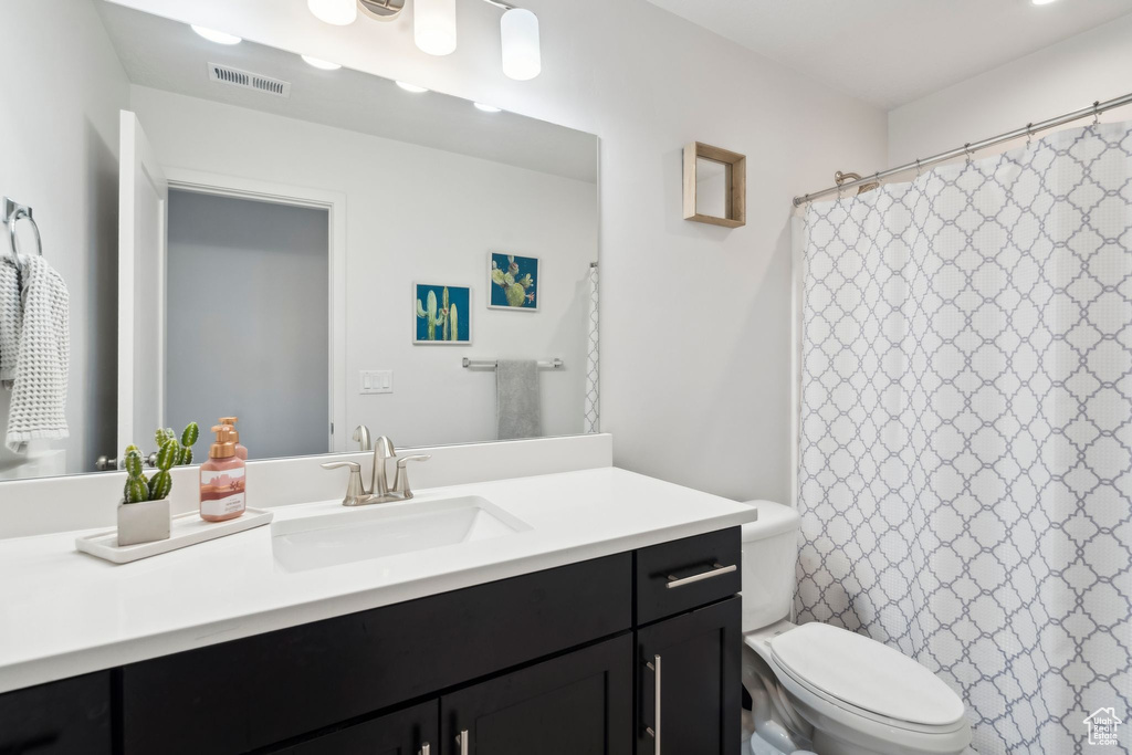 Bathroom featuring vanity, toilet, and a shower with shower curtain