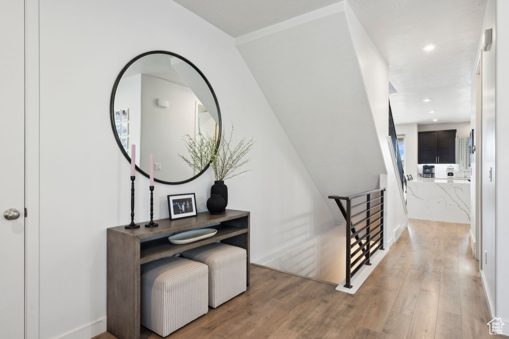 Hall with an upstairs landing, wood finished floors, and recessed lighting