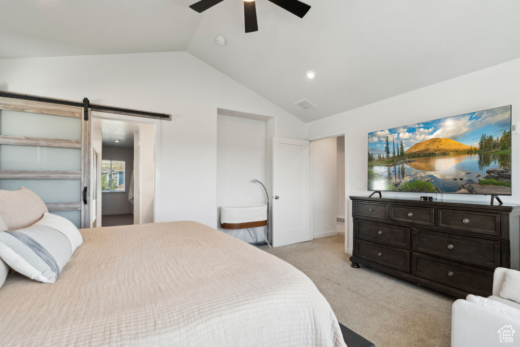 Bedroom featuring light carpet, vaulted ceiling, a barn door, and ceiling fan