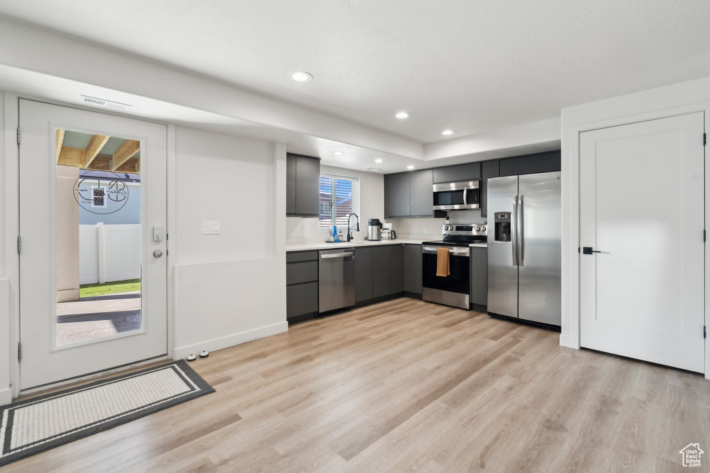 Kitchen featuring stainless steel appliances, gray cabinets, light wood-style floors, a sink, and recessed lighting