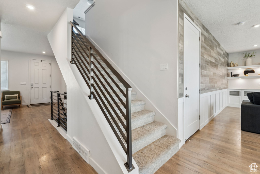 Stairs featuring wood finished floors and recessed lighting