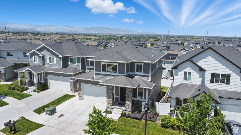 View of front of property featuring a residential view, driveway, stone siding, and a mountain view
