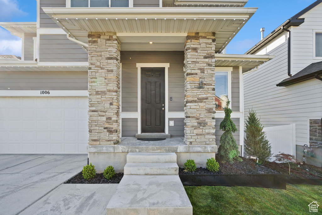 Entrance to property with an attached garage, concrete driveway, and stone siding