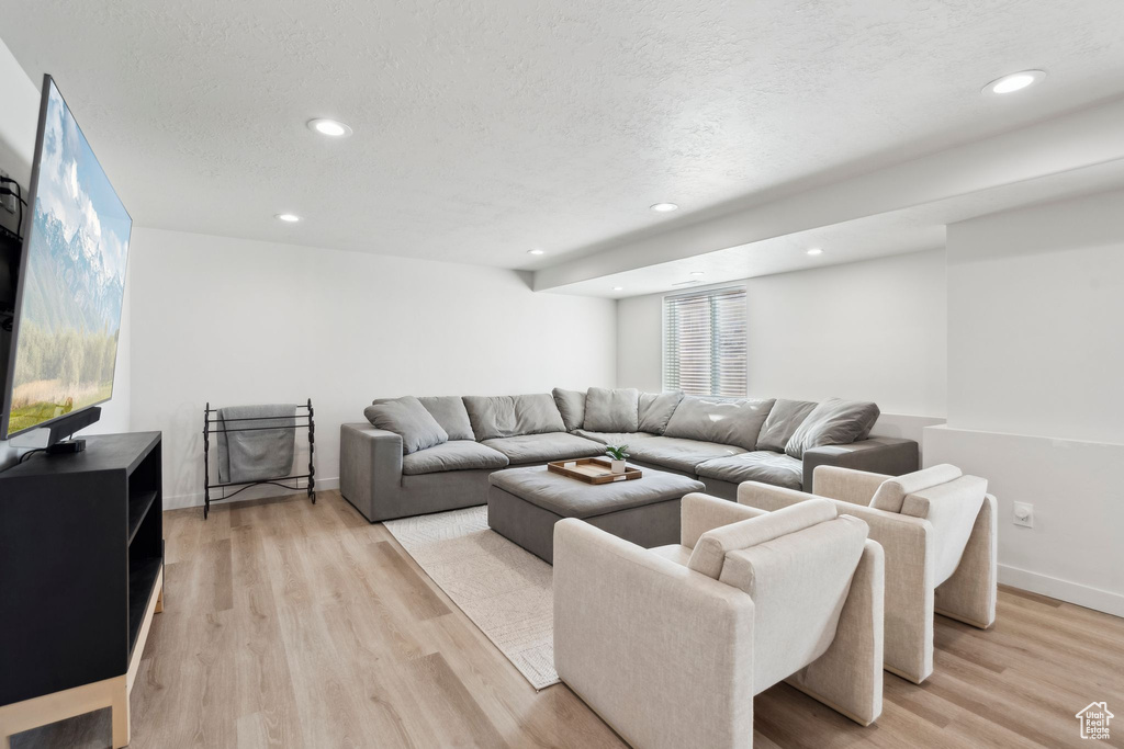 Living room featuring light wood-type flooring, recessed lighting, a textured ceiling, and baseboards