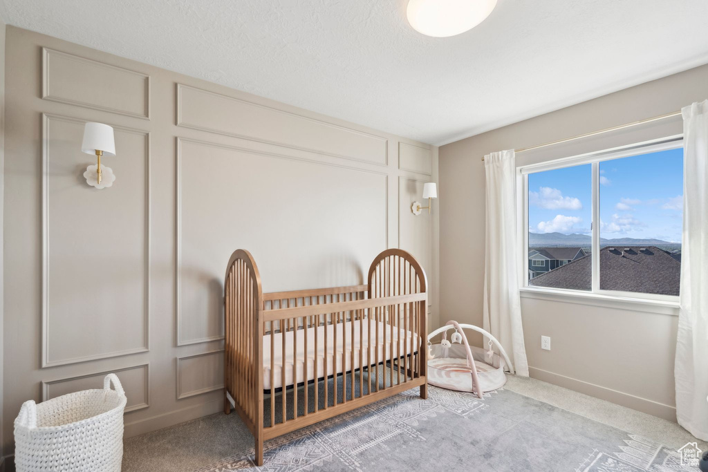 Carpeted bedroom with a decorative wall and a nursery area