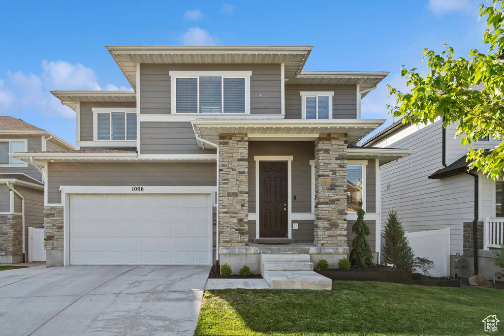 View of front of home featuring a garage, concrete driveway, and stone siding