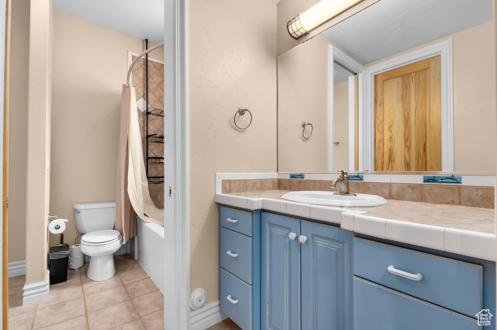 Bathroom featuring vanity, tile patterned flooring, shower / bath combination with curtain, and toilet